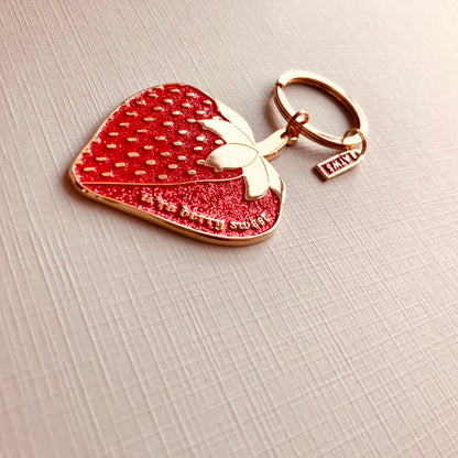 Schlüsselanhänger in Form einer roten Erdbeere mit goldfarbenen Details und dem Schriftzug 'u’re berry Sweet '