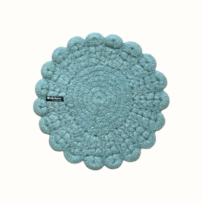 Eine handgehäkelte Sitzunterlage in zartem Lavendel mit romantischen Blütensaum. Das zentrale Häkelmuster in Kreisform bildet einen harmonischen Kontrast zum verspielten Rand. 