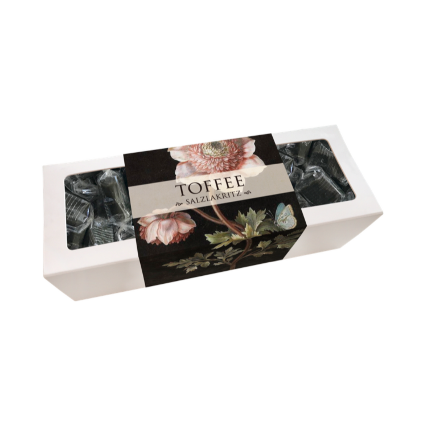 Weiße rechteckige Verpackung mit durchsichtiger Folie, schwarzem Etikett mit Blumenmotiv und Schriftzug 'TOFFEE mit SALZLAKRITZ'.