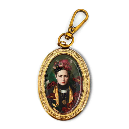 Ovaler goldfarbener Schlüsselanhänger mit einem Porträt einer Frau in traditioneller Kleidung und Blumenschmuck im Haar