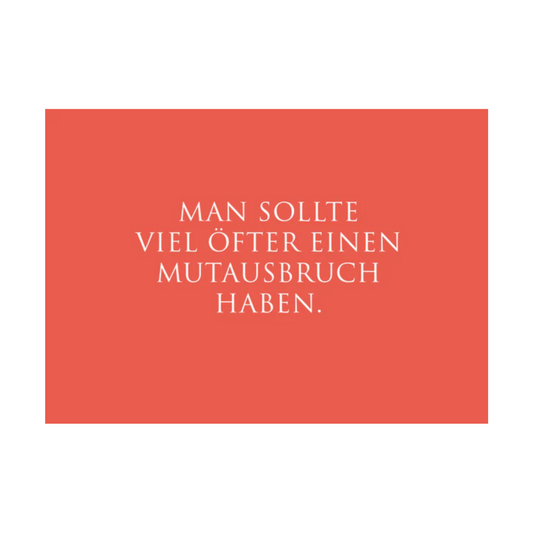 Dieses Bild zeigt eine Postkarte mit deutschem Text auf korallenrotem Hintergrund. Der weiße Text in klarer, moderner Schrift trägt die folgende Botschaft:
„MAN SOLLTE
VIEL ÖFTER EINEN
MUTAUSBRUCH
HABEN.“
