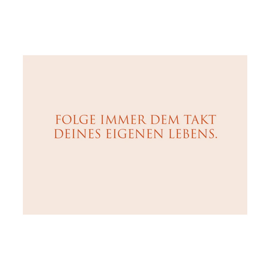 Dieses Bild zeigt eine Postkarte mit deutschem Text auf einem zart rosafarbenem Hintergrund. Die Karte enthält roten Text in einer klaren, modernen Schriftart mit der folgenden Botschaft in kurzen Sätzen: “FOLGE IMMER DEM TAKT DEINES EIGENEN LEBENS.“