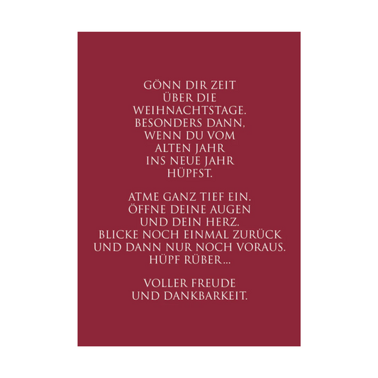 Weinrote Postkarte mit weißer Schrift und dem Text: “Gönn Dir Zeit über die Weihnachtstage. Besonders dann, wenn Du vom alten Jahr ins neue Jahr hüpfst. Atme ganz tief ein. Öffne Deine Augen und Dein Herz. Blicke noch einmal zurück und dann nur noch voraus. Hüpf rüber… Voller Freude und Dankbarkeit.“