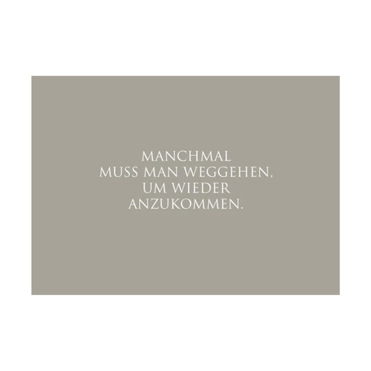 Dieses Bild zeigt eine Postkarte mit deutschem Text auf graugrünem Hintergrund. Der weiße Text in klarer, moderner Schrift trägt die folgende Botschaft:
„MANCHMAL MUSS MAN WEGGEHEN, UM WIEDER ANZUKOMMEN.“