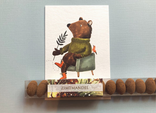 Lange, transparente Verpackung mit einer Reihe brauner Zimtmandeln und einem Etikett mit dem Schriftzug 'ZIMTMANDEL'.