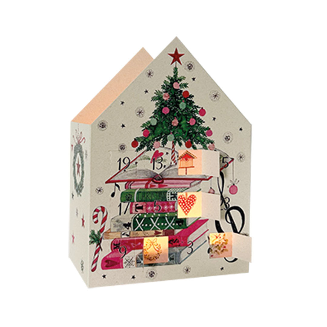 Leuchtender Adventskalender in Hausform von der Edition Gollong, der einen Stapel bunter Bücher mit einem Weihnachtsbaum obenauf zeigt.