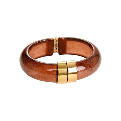 Warmer bernsteinfarbener Glitzer-Armreif mit polierter goldener Metallschnalle.