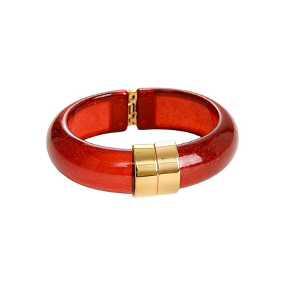 Kräftiger roter transparenter Armreif mit Glitzerpartikeln und goldener Schließe.