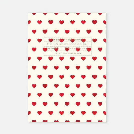 Frontansicht eines A5-Notizhefts mit einem Muster aus vielen kleinen roten Herzen auf naturweißem Grund. In der Mitte befindet sich ein dezenter goldener Textrahmen mit der Aufschrift „Every Day Notebook - 64 dotted pages - by All the ways to say“.