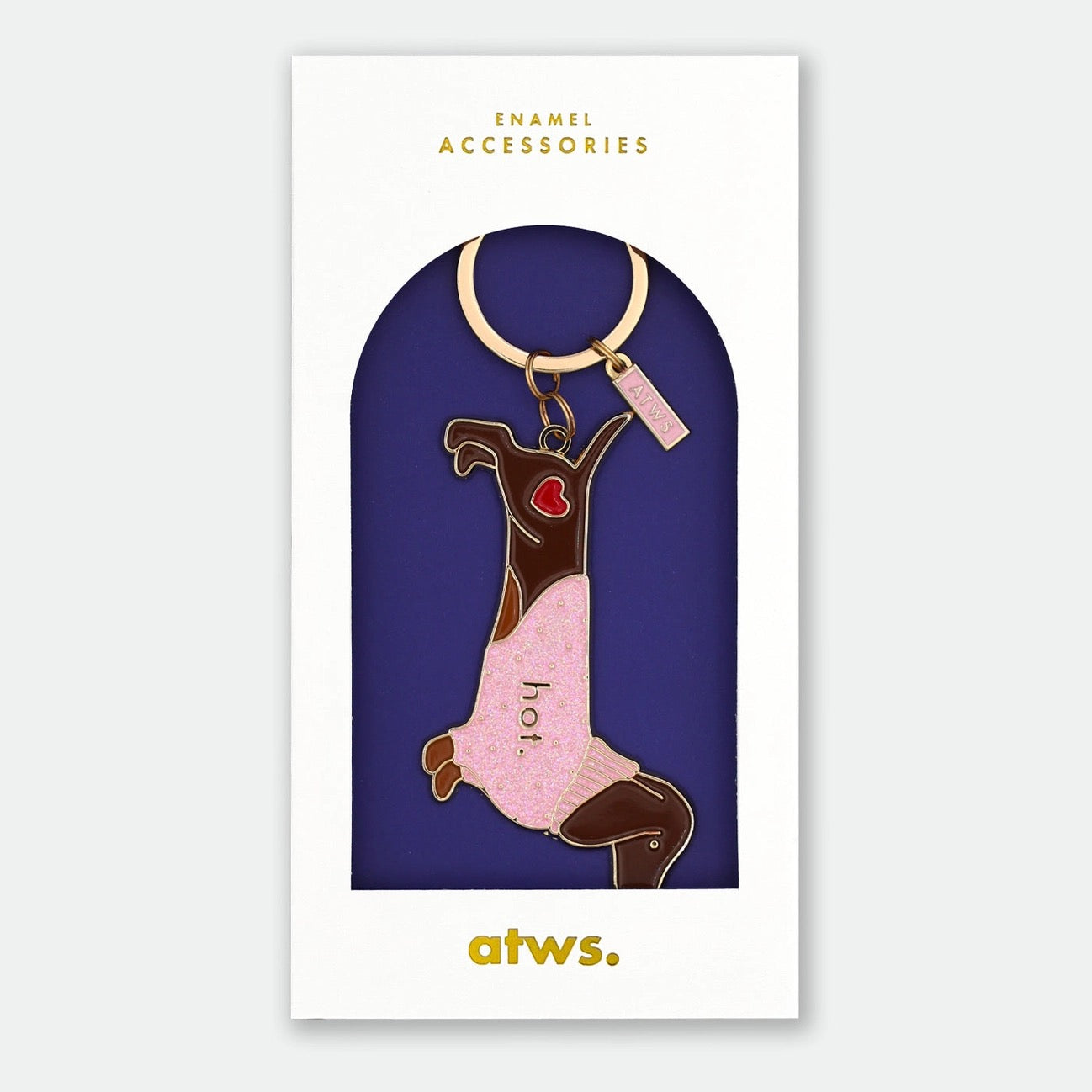 All the ways to Say Emaille-Schlüsselanhänger „Hot Dog“: Ein brauner Dackel mit einem rosa Glitzer-Pullover und der Aufschrift „hot.“, präsentiert in einer weißen Geschenkverpackung mit goldenem Logo.