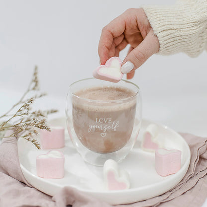 Marshmallow-Herz wird in eine Tasse Kakao mit der Aufschrift „Love yourself“ gelegt.