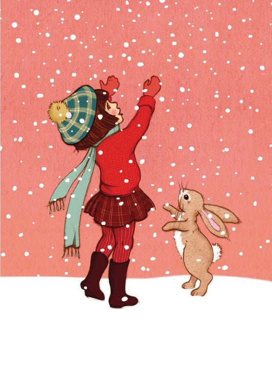 Ein Mädchen mit Mütze, Schal, rotem Pullover und Rock steht im Schnee und streckt die Arme nach oben, während ein Kaninchen auf den Hinterbeinen neben ihr steht.