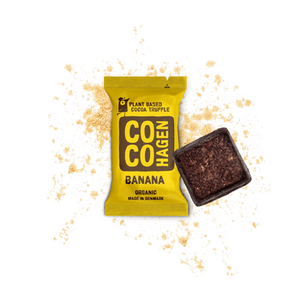 Pflanzlicher Bio-Bananen-Kakaotrüffel von CocoHagen in leuchtend gelber Verpackung mit Bananenpulver auf weißem Hintergrund, unverpackter dunkler Schokoladentrüffel neben der Verpackung, hergestellt in Dänemark