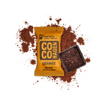 CocoHagen – Bio-Orangen-Kakaotrüffel in orangefarbenerVerpackung mit Kakaopulver auf weißem Hintergrund, unverpackte dunkle Schokoladentrüffel neben der Verpackung, hergestellt in Dänemark