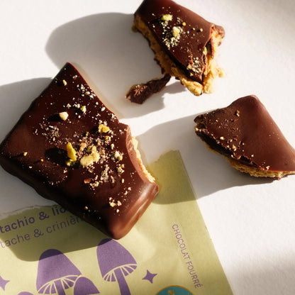 Nahaufnahme von dunklen Schokoladenstücken mit cremiger Pistazienfüllung und gehackten Pistazien als Topping.