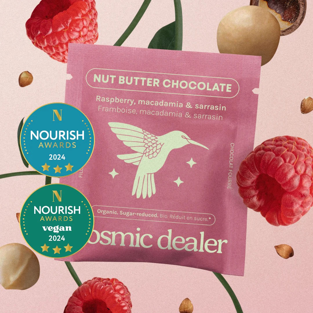Pinke Verpackung der Cosmic Dealer Himbeere & Macadamia Schokolade mit Kolibri-Illustration.