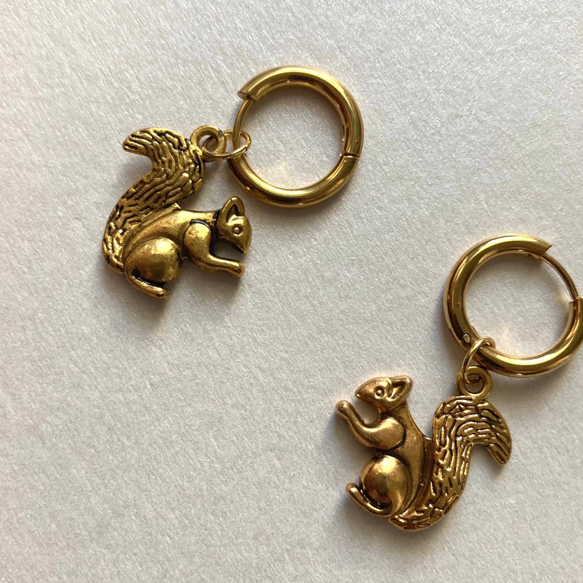 Goldfarbene Creolen mit Anhängern in Form von Eichhörnchen mit buschigem Schwanz.