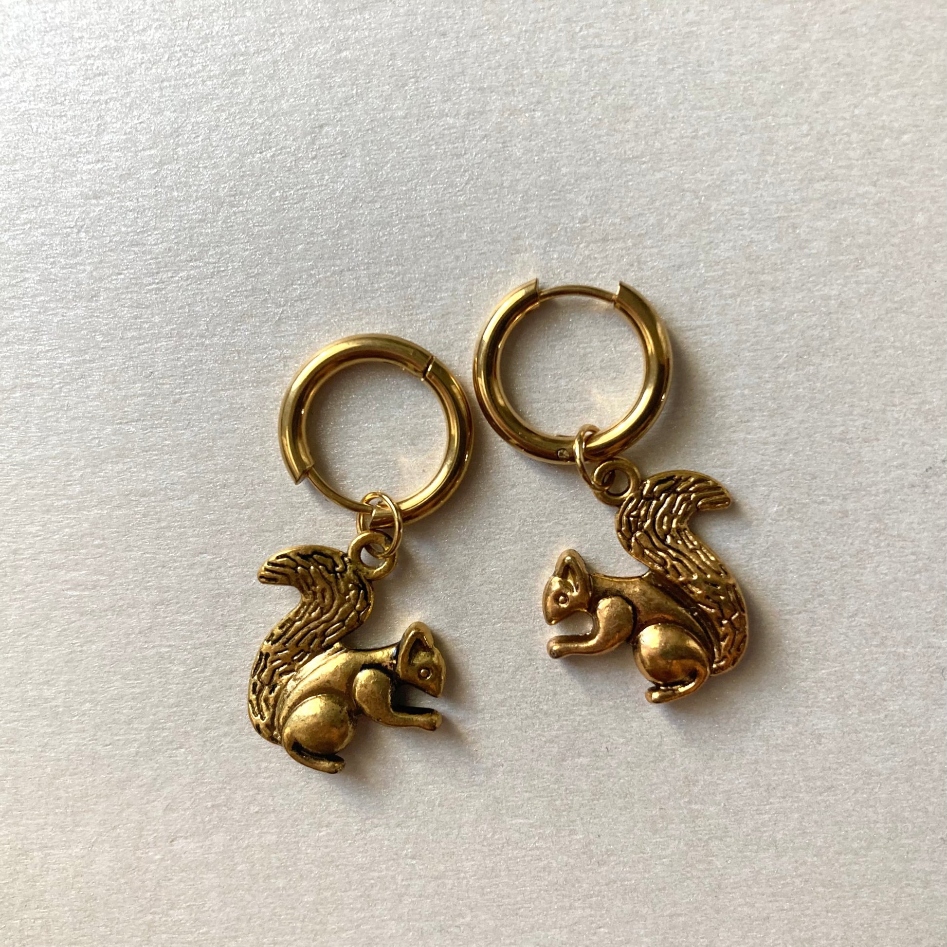 Goldfarbene Creolen mit Anhängern in Form von Eichhörnchen mit buschigem Schwanz.
