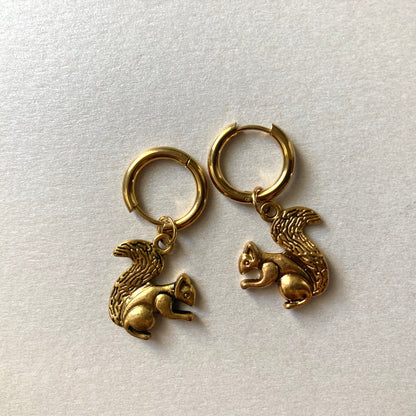 Goldfarbene Creolen mit Anhängern in Form von Eichhörnchen mit buschigem Schwanz.
