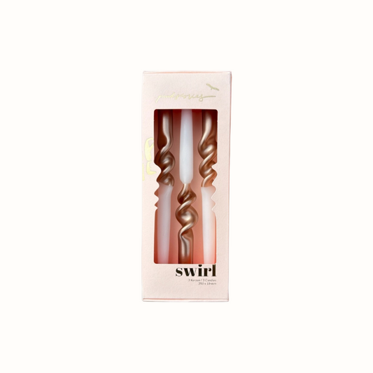 Drei goldfarbene, spiralförmige Kerzen in einer hellrosa Verpackung mit Sichtfenster und der Aufschrift 'swirl'.