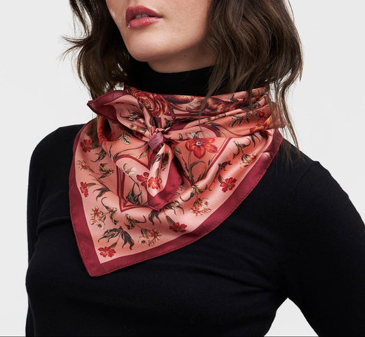 Quadratisches Tuch mit rotem Rand und floralem Muster in Rot, Blau und Beige, symmetrisch angeordnet.