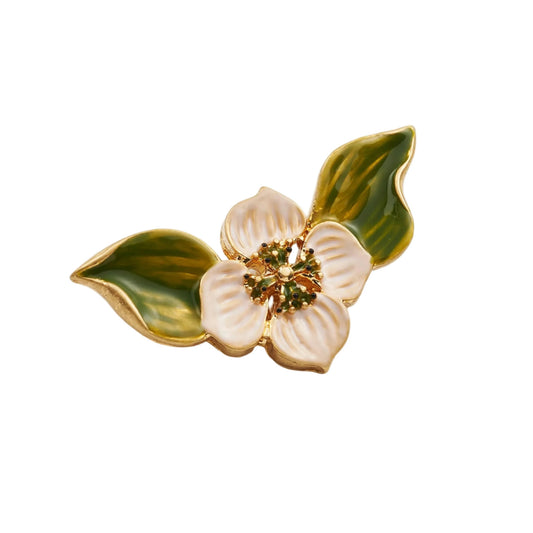 Goldfarbene Brosche in Form einer Blüte mit weißen Blütenblättern und zwei grünen Blättern, verziert mit kleinen grünen Punkten in der Mitte.