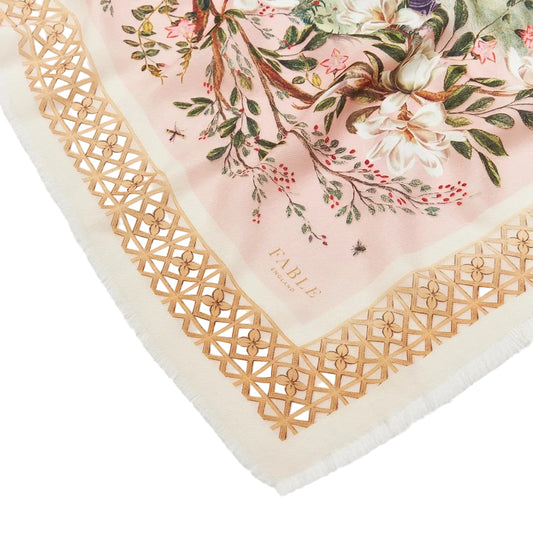 Nahaufnahme der Ecke eines Fable England Schals in Rosa mit Magnolienblüten, kleinen Käfern und einer goldgelben Gitterbordüre mit Fransen.