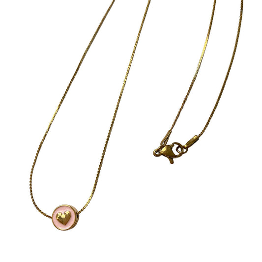 Eine sehr feine goldene Gliederkette flach liegend auf weißem Untergrund. Der runde Anhänger hat eine zartrosa Emaille-Füllung, in deren Mitte ein kleines, plastisches goldenes Herz eingearbeitet ist.