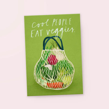 Grüne Karte mit der Aufschrift 'Cool people eat veggies' und einer Netz-Einkaufstasche voller Gemüse wie Karotte, Radieschen und Salat