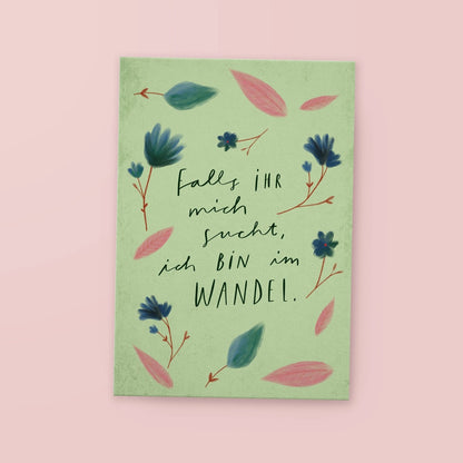 Grünes Poster mit dem Text 'Falls ihr mich sucht, ich bin im Wandel' umgeben von blauen und rosa Blättern und Blumen