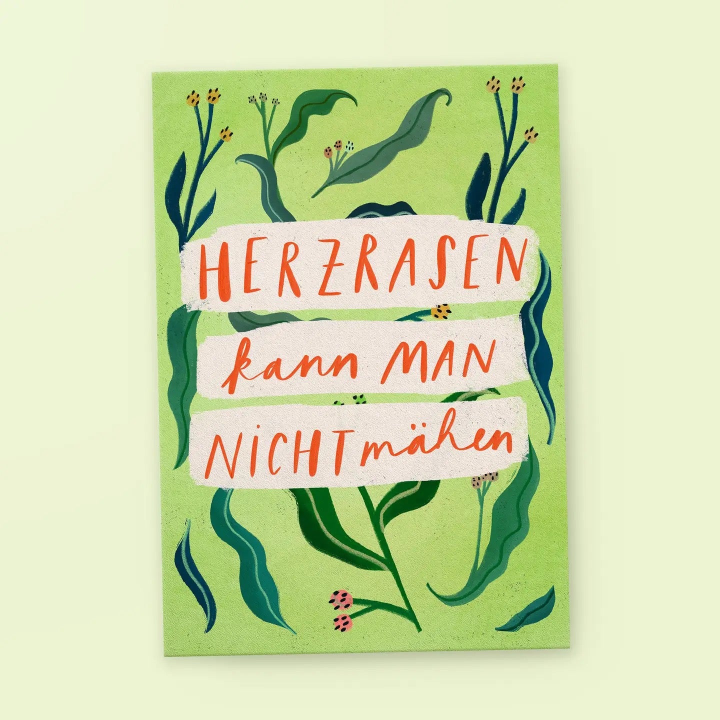 Eine Postkarte mit hellgrünem Hintergrund, verziert mit gezeichneten Pflanzen und Blüten. In der Mitte stehen auf drei weiß hinterlegten Pinselstrichen die Worte: „HERZRASEN kann MAN NICHT mähen“.