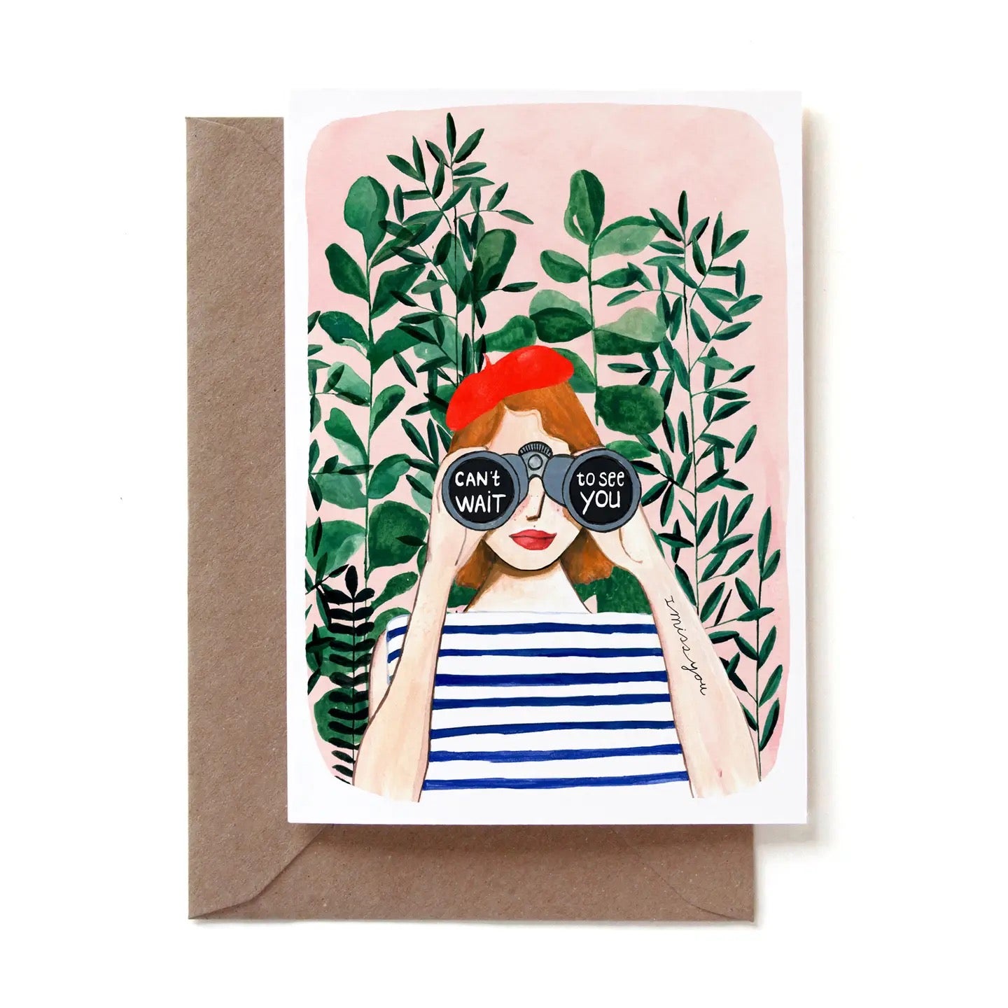 Eine illustrierte Klappkarte mit einer rothaarigen Frau, die ein rotes Barett, ein blau-weiß gestreiftes T-Shirt und roten Lippenstift trägt. Sie blickt durch ein Fernglas direkt nach vorne. Auf den Linsen des Fernglases steht der weiße Text „CAN'T WAIT to see YOU“. Auf ihrem linken Unterarm ist das Tattoo „I miss you“ zu sehen. Im Hintergrund befinden sich dichte grüne Pflanzenzweige vor einer zartrosa Wand. Die Karte steckt in einem braunen Kraftpapier-Umschlag.