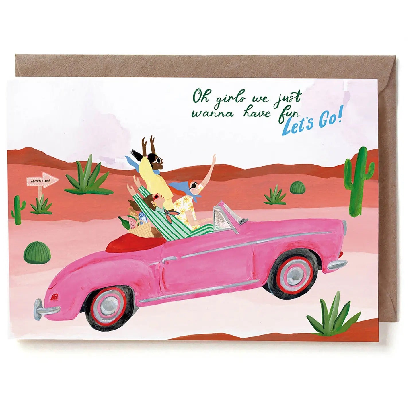 Eine illustrierte Grußkarte im Querformat mit der Aufschrift „Oh girls we just wanna have fun Let's Go!“. Drei Frauen sitzen gut gelaunt in einem pinken Oldtimer-Cabriolet und fahren durch eine Wüstenlandschaft mit Kakteen und Sukkulenten. Auf der Rückbank steht ein gefüllter Picknickkorb. Ein hölzernes Schild am Wegrand zeigt in Fahrtrichtung und trägt die Aufschrift „ADVENTURE“. Die Karte liegt auf einem braunen Kraftpapier-Umschlag.