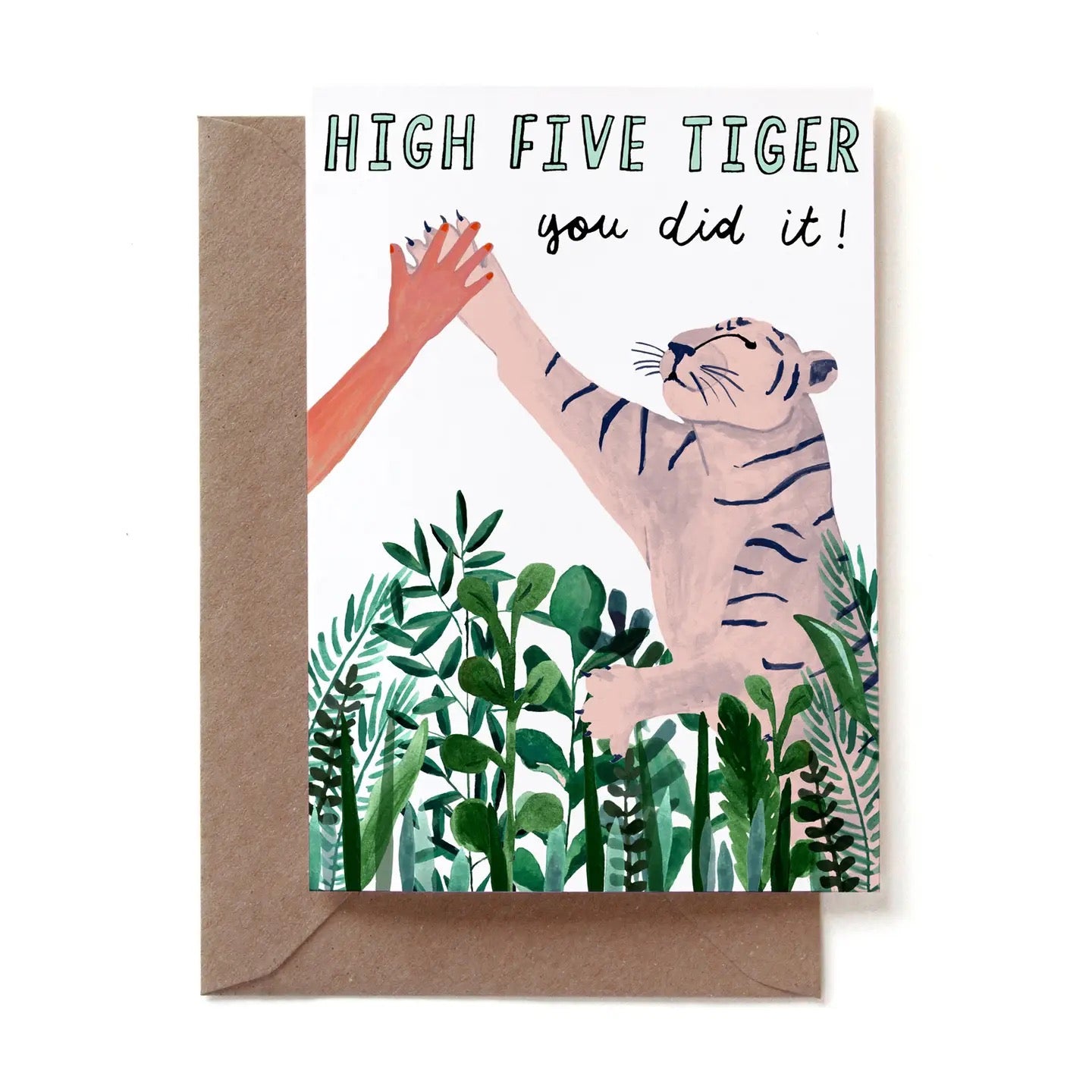 Eine illustrierte Glückwunschkarte mit der Aufschrift „HIGH FIVE TIGER you did it!“. Auf der Karte gibt ein menschlicher Arm mit rot lackierten Fingernägeln einer hellrosa-weißen Tigerpranke ein High Five. Der Tiger schaut glücklich nach oben. Im Vordergrund sind dichte grüne Dschungelpflanzen zu sehen. Die Karte steckt in einem braunen Kraftpapier-Umschlag.