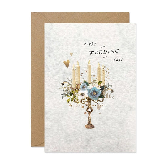 Karte mit einem goldfarbenen Kerzenhalter, vier brennenden Kerzen, blauen Blumen und dem Schriftzug 'happy WEDDING day!'.