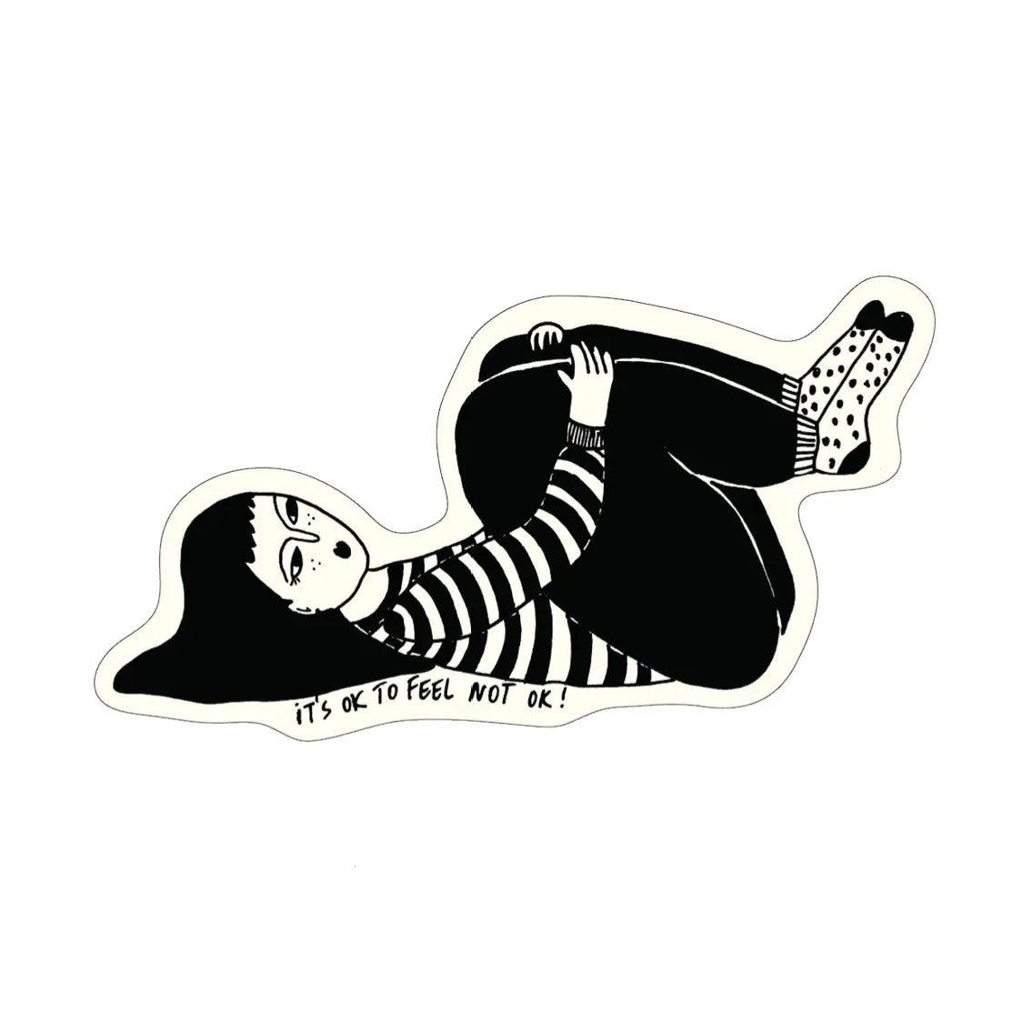 Schwarz-Weiß-Illustration einer Person mit langen dunklen Haaren, gestreiftem Oberteil und gepunkteten Socken, die auf dem Rücken liegt und ihre Beine an den Körper heranzieht. Darunter steht der handgeschriebene Schriftzug „IT'S OK TO FEEL NOT OK!“