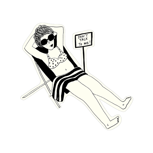 Eine Schwarz-Weiß-Sticker-Illustration einer Frau mit dunkler Lockenmähne und Sonnenbrille. Sie liegt entspannt in einem Liegestuhl, ein gestreiftes Handtuch über den Beinen. Neben ihr steht ein Schild mit der Aufschrift „DON’T TALK TO ME!“.