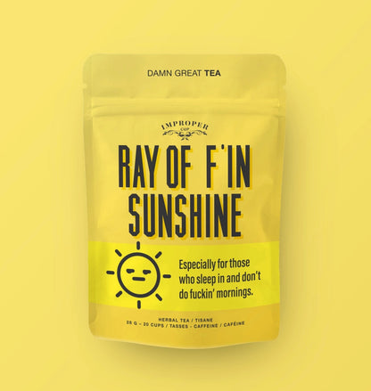 Gelbe Verpackung des Kräutertees „Ray of F'in Sunshine“ von Improper Cup mit einer schlecht gelaunten Sonne als Illustration.
