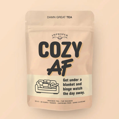 Beigefarbene Verpackung des koffeinfreien Rooibos-Tees „Cozy AF“ von Improper Cup mit einer Strichzeichnung von einem Sofa.
