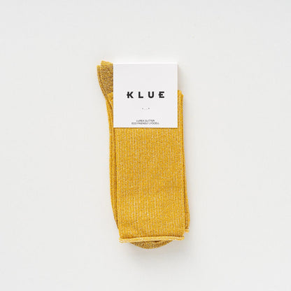 KLUE Lurex-Glitzersocken aus nachhaltigem Bamboo-Lyocell in Gelb mit weißer Papier-Banderole auf weißem Hintergrund.
