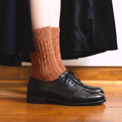 Nahaufnahme der getragenen KLUE DUST STAR Socken in Orange aus Seide und Wolle, kombiniert mit einem stylischen Halbschuh.