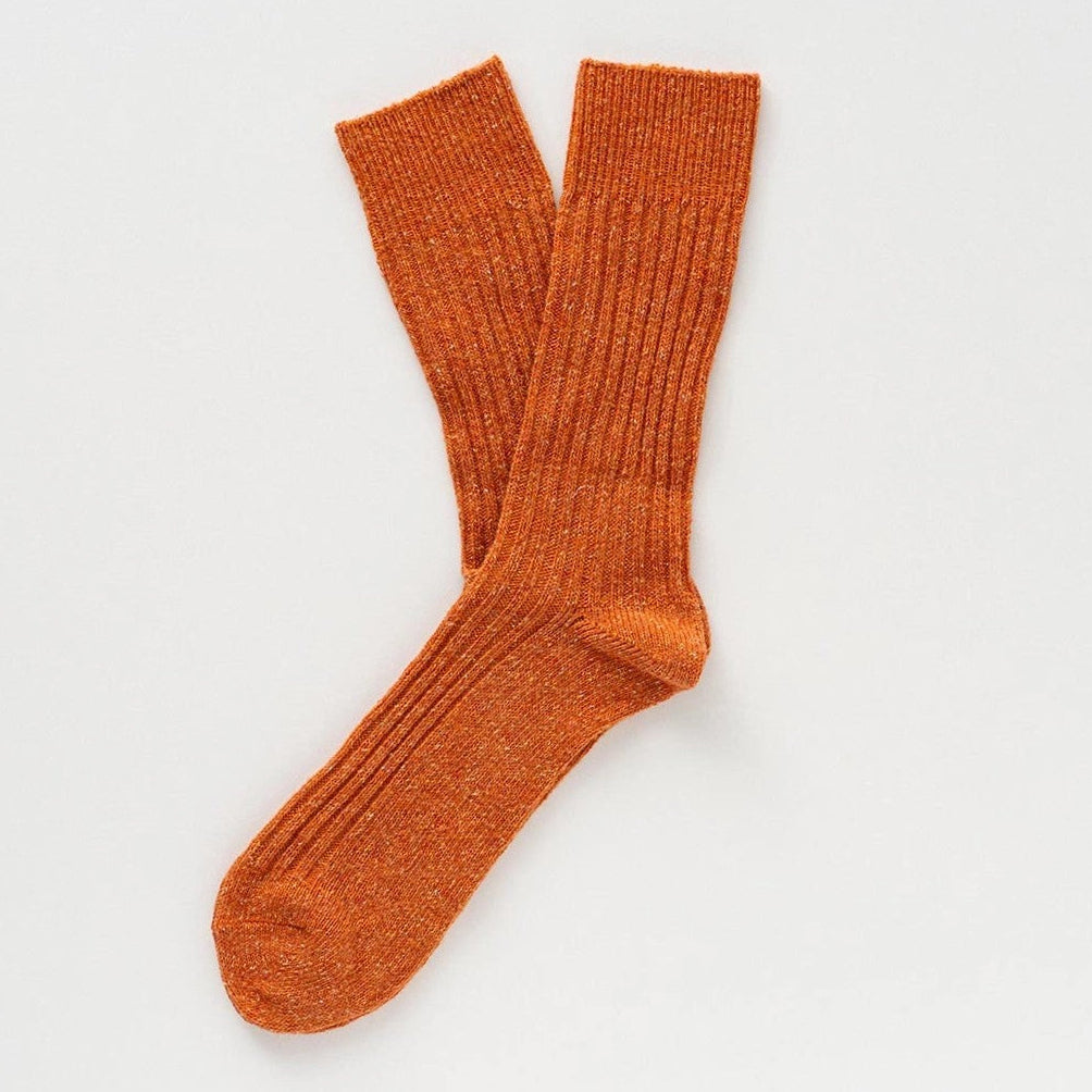 Flach liegende KLUE DUST STAR Design-Socken in Orange die die feine, hochwertige Strick-Struktur des Seiden-Woll-Gemischs zeigen.