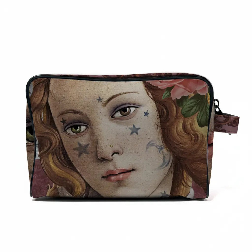 Nahaufnahme der Kulturtasche von voglio bene mit Fokus auf das Gesicht der Venus im Renaissance-Stil. Zu sehen sind filigrane Stern- und Mond-Tattoos auf den Wangen, eine zarte Blume im Haar und die schwarze Reißverschluss-Einfassung.
