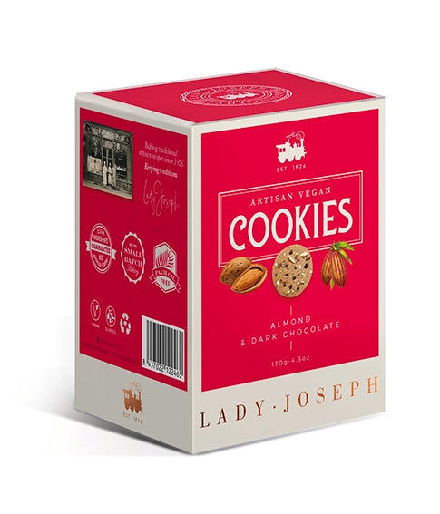 Dreidimensionale Produktansicht einer rechteckigen Keksschachtel von „Lady Joseph“. Die Vorderseite ist in kräftigem Magenta-Rot gehalten mit cremeweißem Rahmen. Der Aufdruck lautet „Artisan Vegan Cookies - Almond & Dark Chocolate“. Darunter sind Illustrationen von einer Mandel, einem Keks und einer Kakaobohne zu sehen. Auf der Seitenseite befinden sich Produktsymbole wie ein Barcode, ein Vegan-Siegel und Qualitätsversprechen.