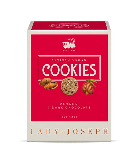 Frontale Produktansicht der Cookie-Verpackung der Marke „Lady Joseph“. Im Zentrum des magentaroten Feldes steht der weiße Schriftzug „ARTISAN VEGAN COOKIES“ sowie darunter „ALMOND & DARK CHOCOLATE 130g“. In der Mitte sind kleine Grafiken einer geöffneten Mandel, eines Kekses und einer Kakaobohne abgebildet. Am unteren cremefarbenen Rand steht der Markenname „LADY JOSEPH“.