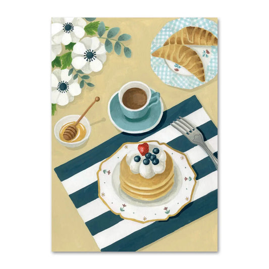Eine helle Illustration eines Frühstückstisches von oben. Auf einer blau-weiß gestreiften Serviette steht ein Teller mit einem Stapel Pfannkuchen, die mit Sahne und Blaubeeren garniert sind. Daneben befinden sich eine Tasse Kaffee, ein Schälchen mit Honig und Honiglöffel sowie ein kleiner Teller mit zwei Croissants auf einem karierten Tuch. Weiße Blumen dekorieren die Szene.