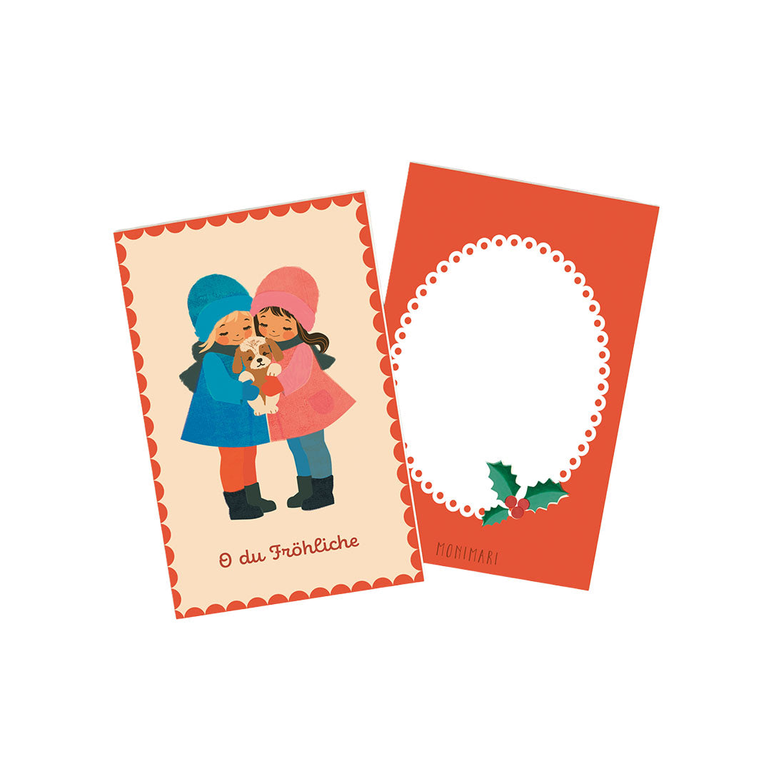 Eine illustrative Minikarte auf einem hellen Hintergrund mit einem dekorativen roten, gewellten Rand. Zwei Kinder, eins in einem blauen und eins in einem rosafarbenen Outfit, stehen in der Mitte und halten gemeinsam einen kleinen, hellbraunen Hund. Unten steht in geschwungener Schrift „O du Fröhliche“.