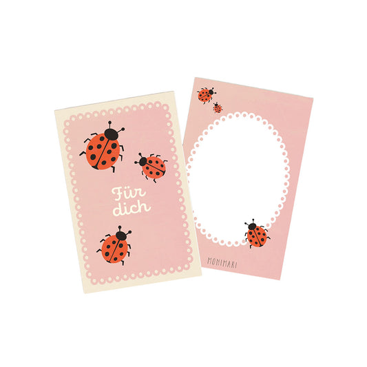 Minikarte von Monimari in zartem Rosa mit rot-schwarzen Marienkäfern. Vorderseite: Mehrere Marienkäfer und der Schriftzug „Für dich“ umgeben von einem geperlten Rand. Rückseite: Rosafarbener Hintergrund mit weißem, geperltem Oval-Rahmen und einem Marienkäfer unten rechts.