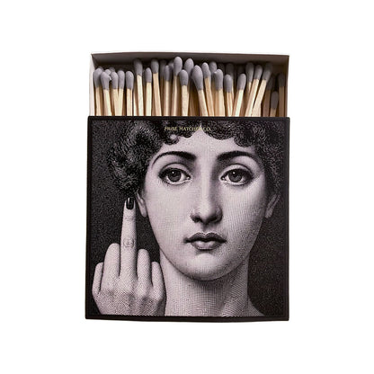Vorderseite einer schwarzen Muse Matches Co. Streichholzschachtel mit dem Schwarz-Weiß-Porträt einer Frau, die den Mittelfinger zeigt, und grauen Streichhölzern.