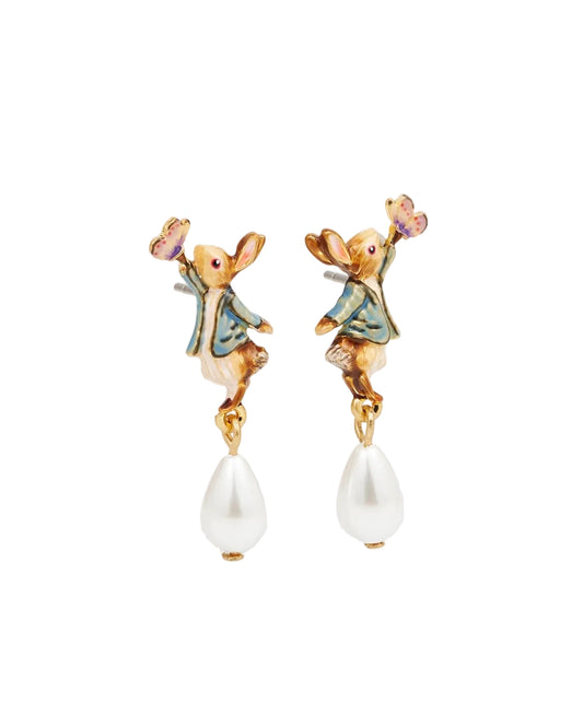 Draufsicht auf ein Paar goldfarbene Ohrstecker auf weißem Hintergrund. Die Ohrringe zeigen detaillierte Hasen-Figuren in blauen Jacken, die nach kleinen Schmetterlingen greifen. An den Pfoten der Hasen hängt jeweils eine elegante, weiße Tropfenperle. Die bunten Emaille-Details in Blau, Braun und Rosa sind deutlich sichtbar.